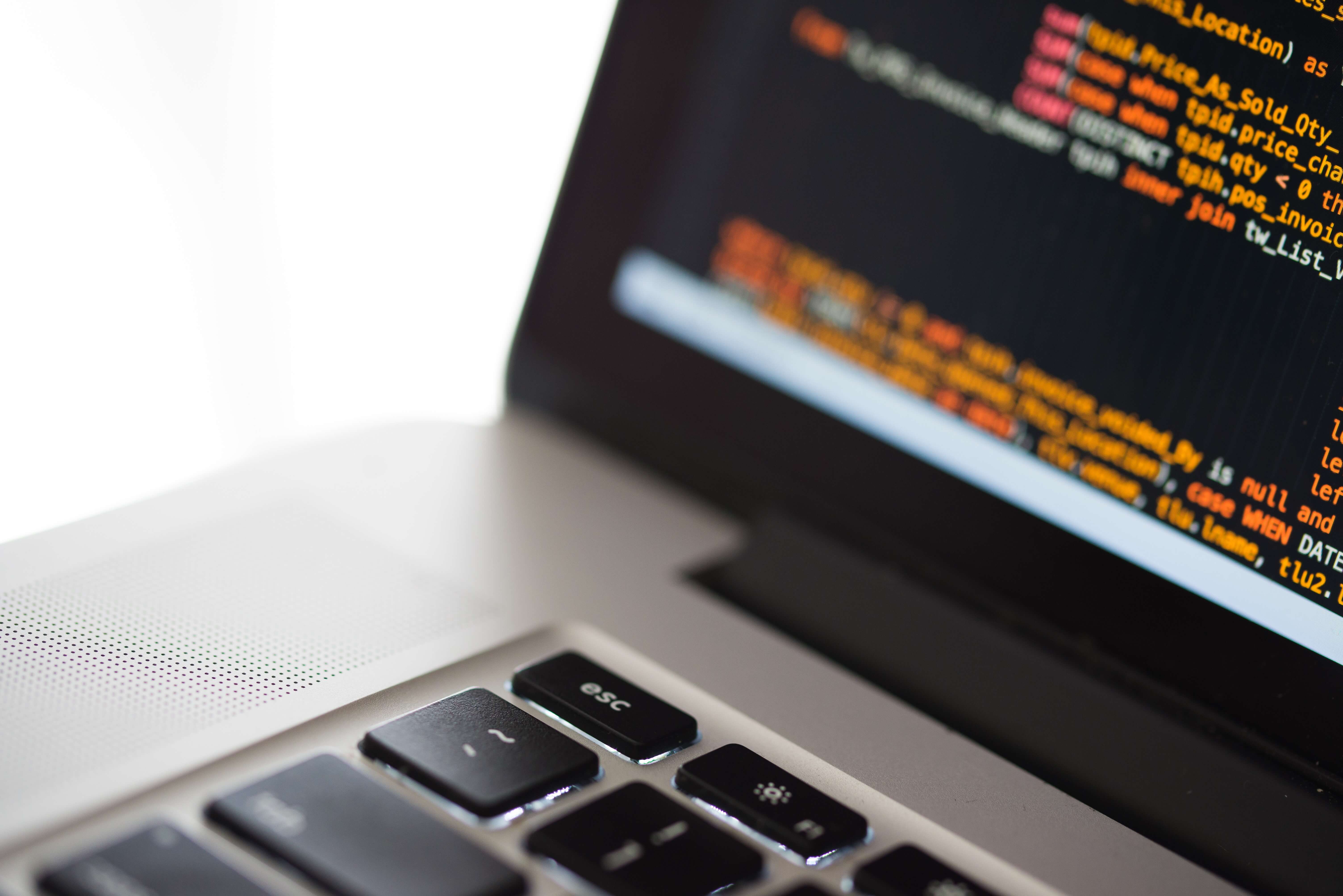 A silver laptop displaying some programming code.